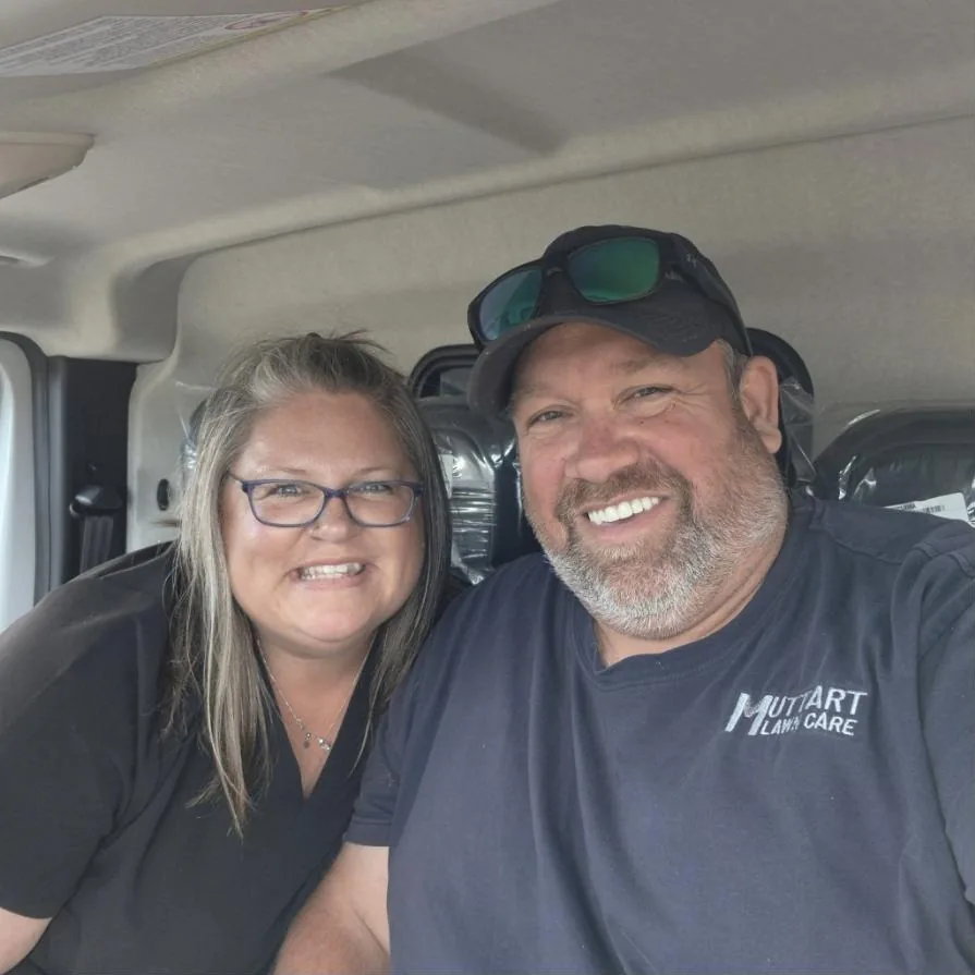 Courtney and Andrew Muttart smiling in the cab of the Zoomie Bus van